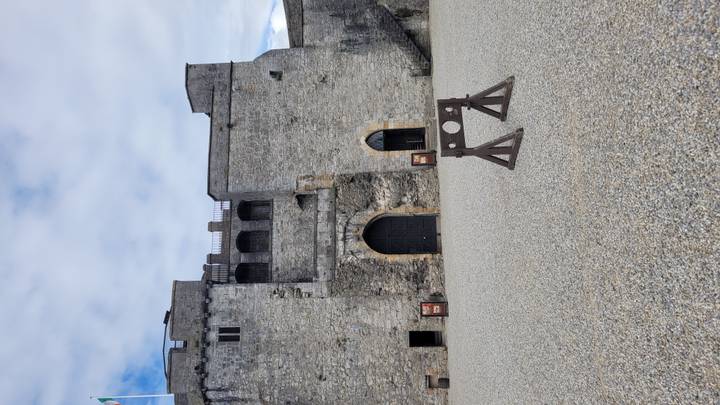 Stone courtyard and high keep walls of a medieval castle with a wooden stocks display.
