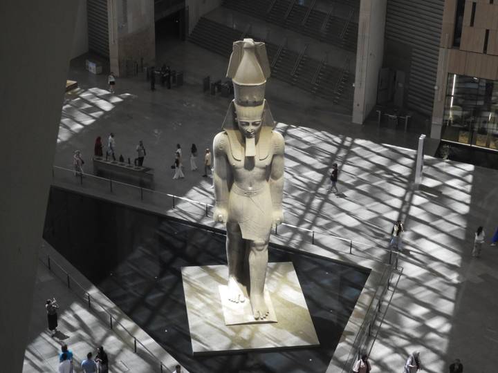 Colossal statue of Ramses II in modern museum atrium lit by patterned skylight