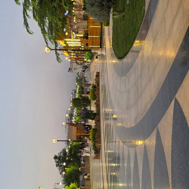 Modern pedestrian promenade at dusk with wet marble tiles and retro lampposts