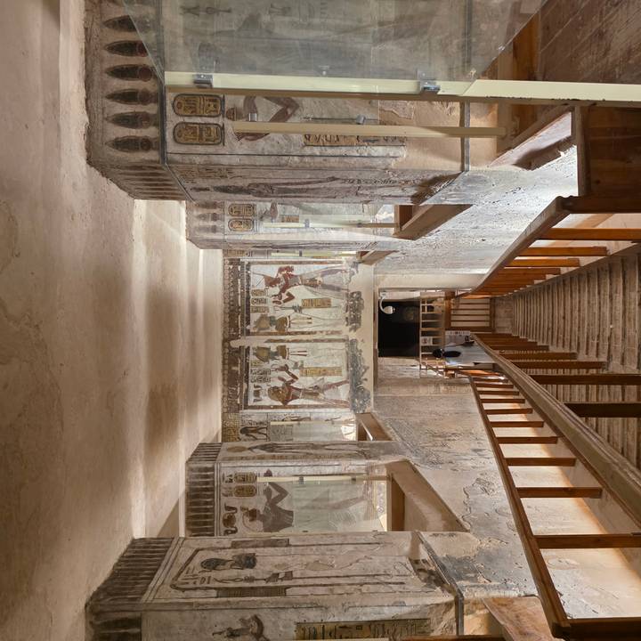 Interior stairway descending into a richly decorated ancient tomb with wall paintings