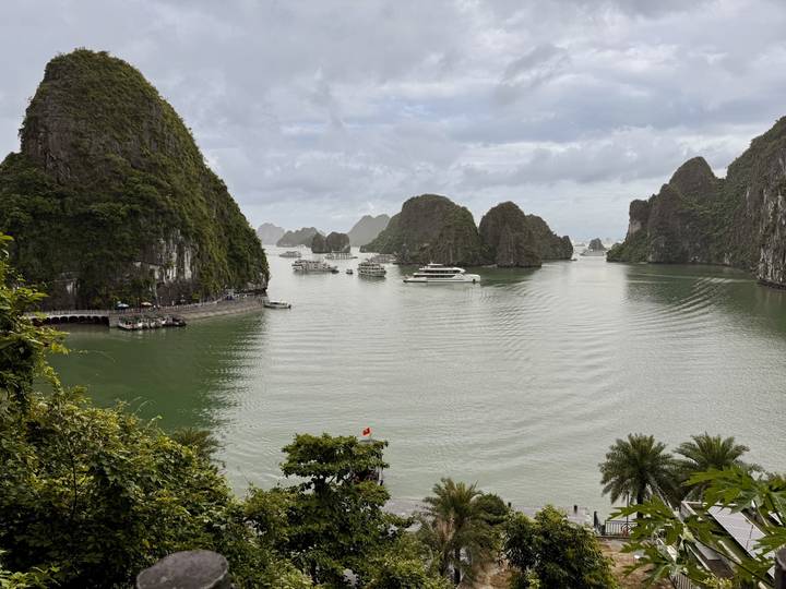 Limestone karst islands rise from emerald waters of a broad bay dotted with cruise boats.