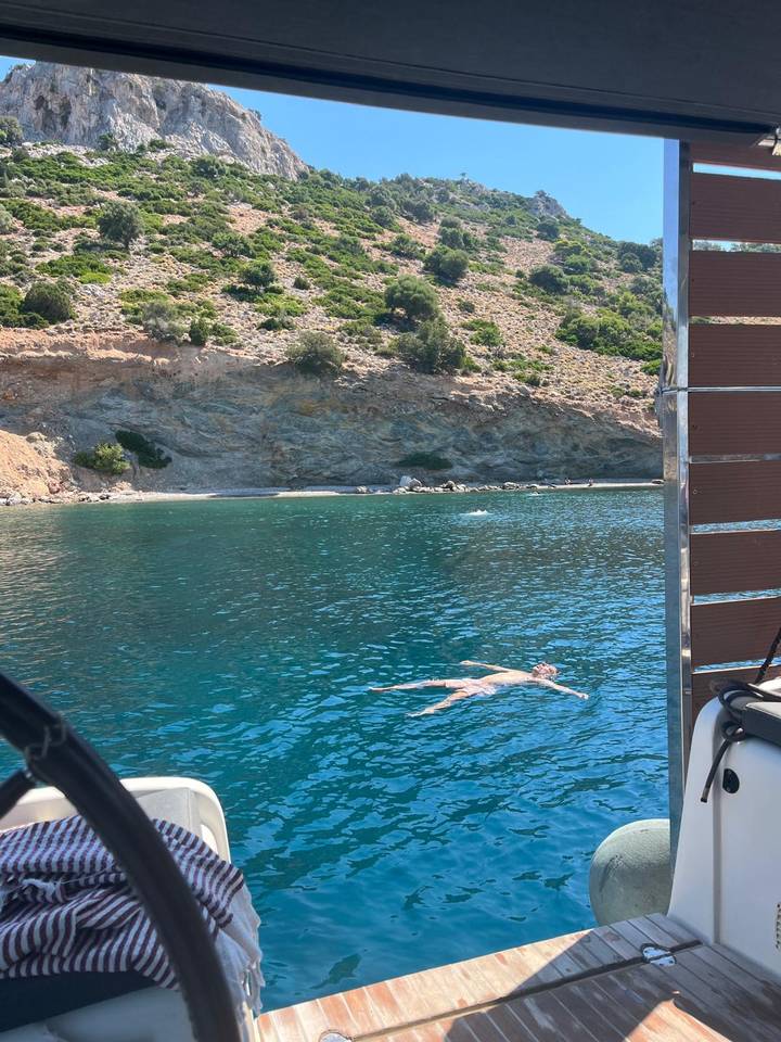 Person floating on their back in clear turquoise cove surrounded by rocky coast.