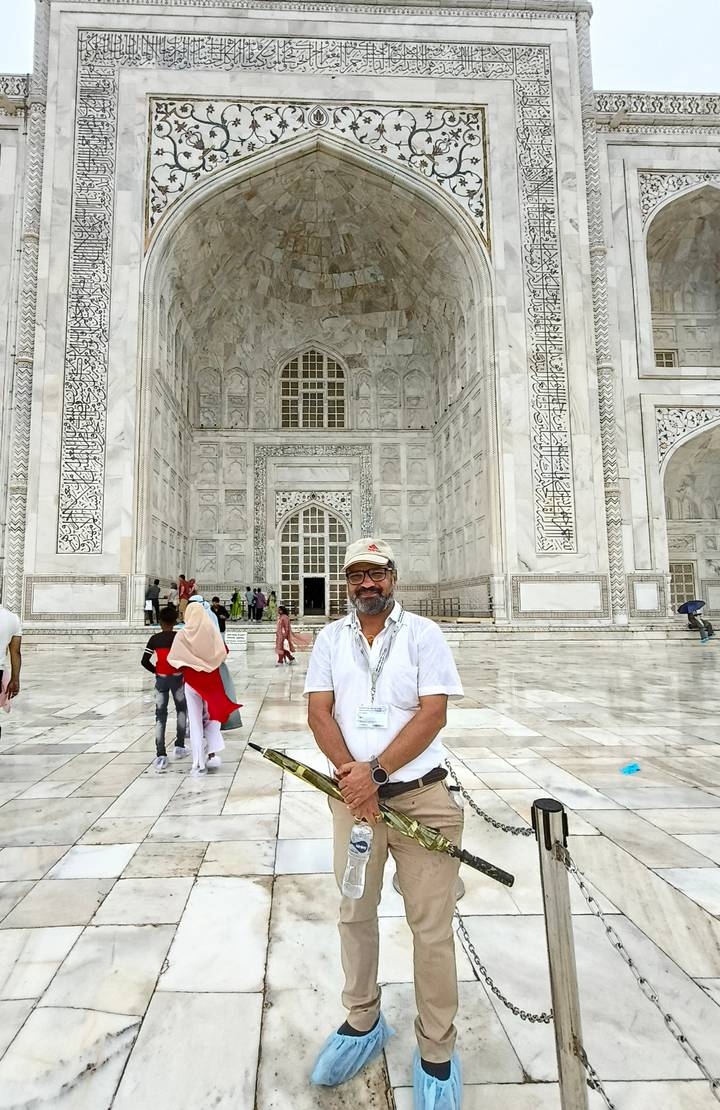A tourist stands in front of an intricately carved marble doorway inside the Taj Mahal complex.