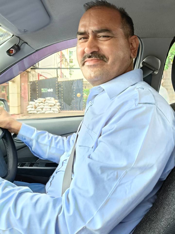 Partial interior view of a car focusing on a driver in a blue shirt and seatbelt.