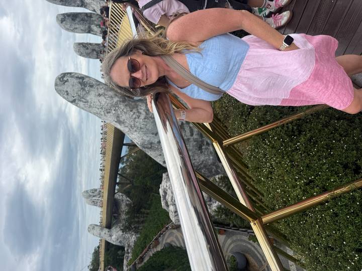 Woman posing on the famous Golden Bridge with giant stone hands in Da Nang.