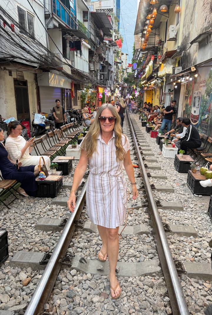 Tourist walks the famous Hanoi Train Street lined with cafés and spectators.