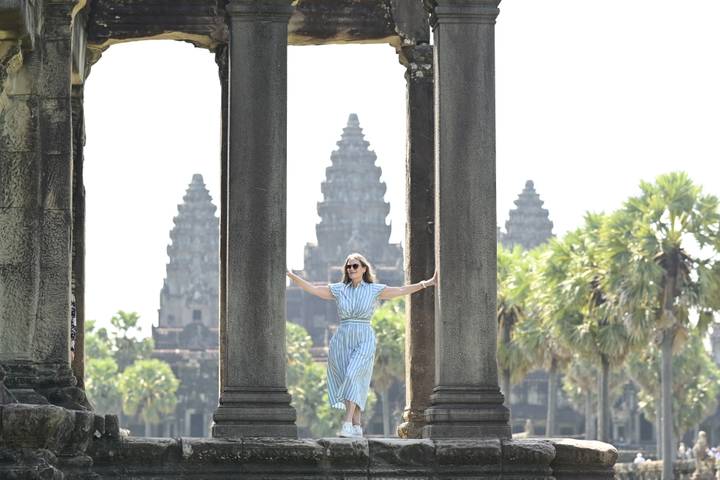 Woman framed by stone columns with the iconic towers of Angkor Wat in the distance.