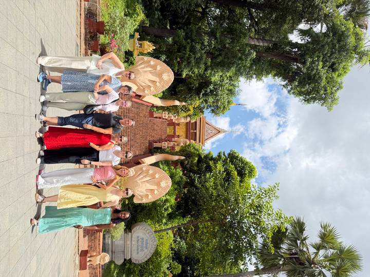 Group photo on a paved path leading to ornate temple stairs flanked by serpent statues.