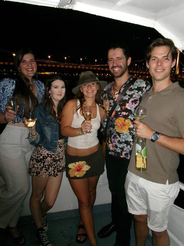 Group of young adults holding wine glasses and smiling during an evening social gathering.