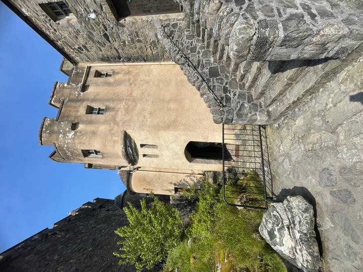Stone stairway and arched doorway of a historic castle turret under blue Highland sky.