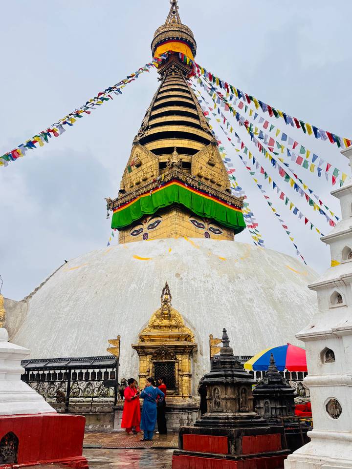 Eyes of Buddha painted on the gilded Swayambhunath stupa tower with colourful prayer flags.