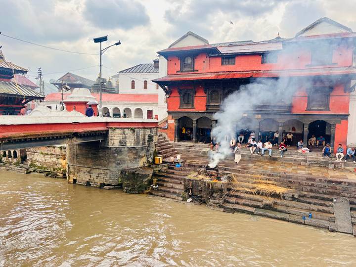 Smoke rising from funeral pyres along the river steps at Pashupatinath temple complex.