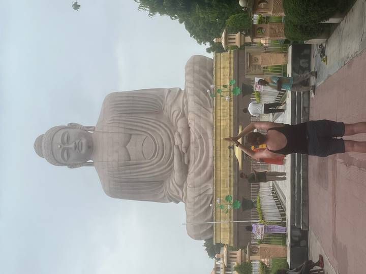 A traveler performs a yoga salute facing the towering Buddha statue at Bodhgaya.