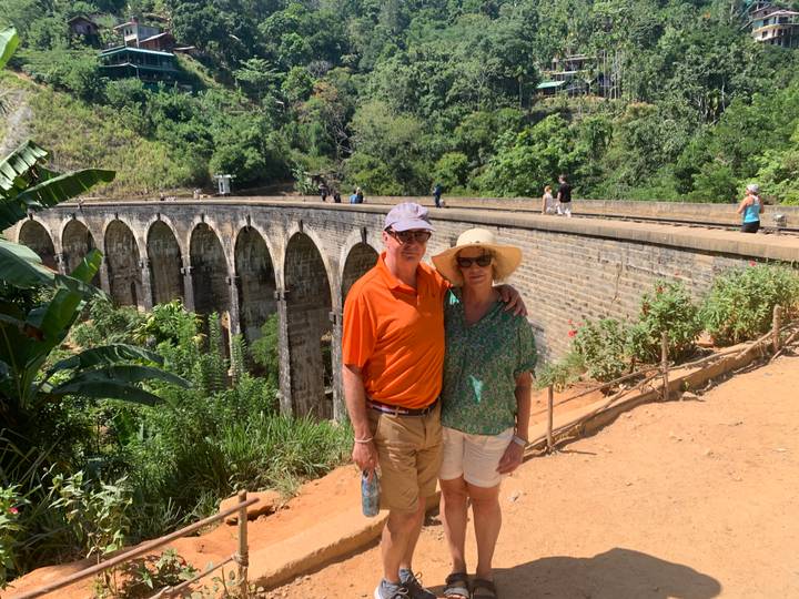 Smiling couple standing on the famous stone Nine-Arch Bridge surrounded by jungle greenery.