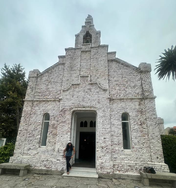 Chapel entirely covered with white seashells creating a textured façade under grey sky.