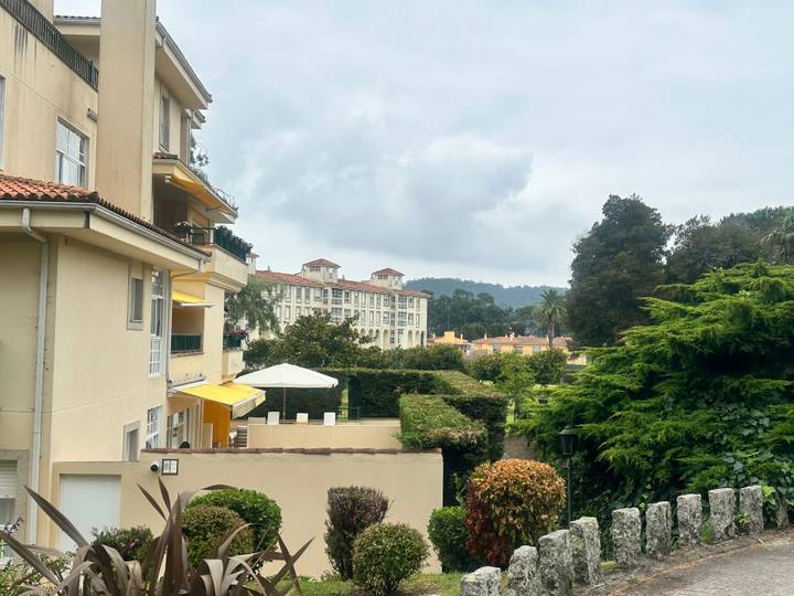 Quiet residential neighbourhood with pastel apartments, gardens and cloudy sky in the background.
