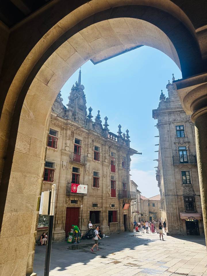 Ornate historic stone buildings with red-framed windows viewed through an archway in old town.
