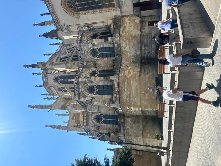 Elaborate Gothic exterior of León Cathedral with tourists walking below on a bright sunny day.