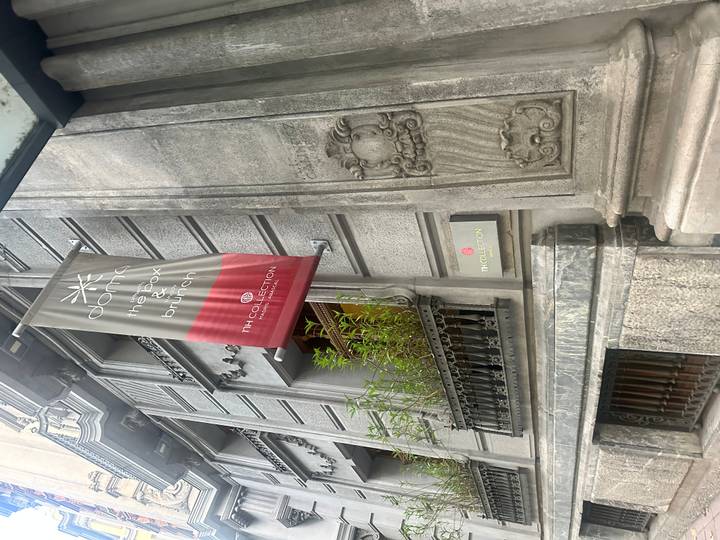 Facade of an ornate grey stone city hotel with TH Collection banner in Madrid.