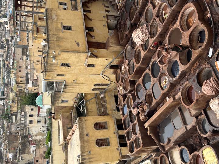 High view of Fes tannery workers treating hides in circular stone vats.