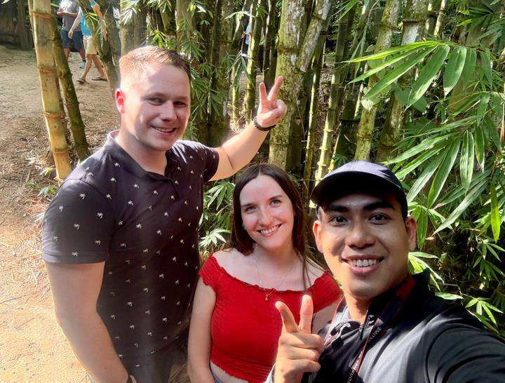 Selfie of three friends flashing peace signs in a bamboo grove.