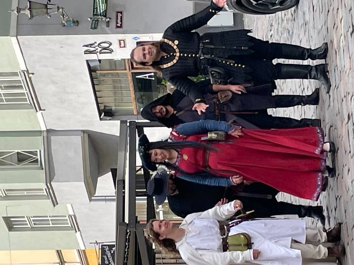 Street performance group dressed in medieval costumes posing in an old town square
