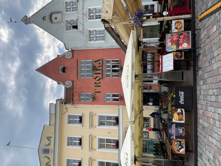 Colorful medieval façades of an old town restaurant square with outdoor menus and umbrellas