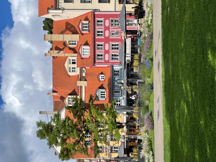 Colorful historic houses with red roofs fronting a green city park on a sunny day