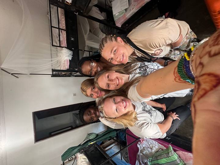 Smiling group selfie of young women inside a bunk-bed hostel room