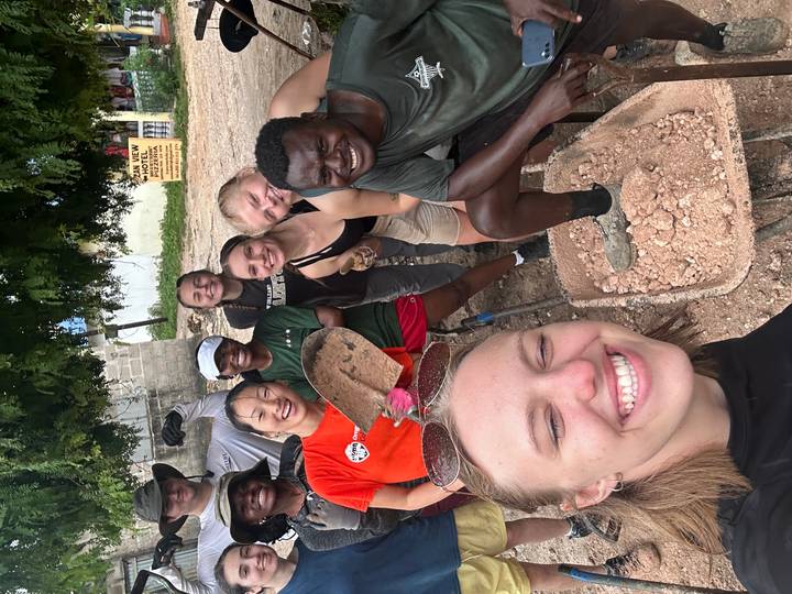 Cheerful volunteers pose with construction tools at a community project site