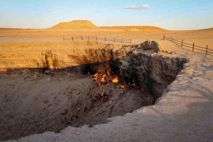 Fiery pit of the Darvaza Gas Crater burning within a vast desert landscape.