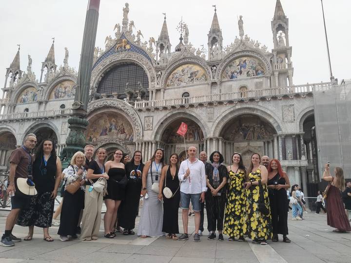 Group stands before ornate façade of St. Mark's Basilica in Venice.