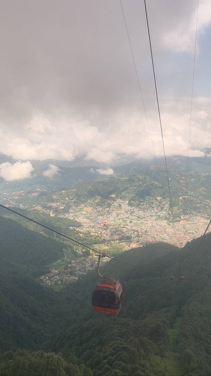 Hazy aerial view of a sprawling Nepalese valley village taken from a cable car high above the hills.