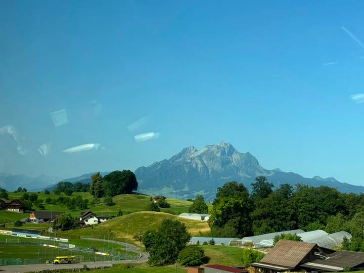 Distant mountain peak viewed through a tour bus window with reflections and glare.