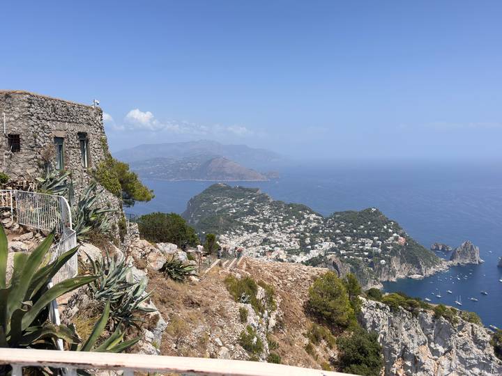 Sweeping view from a cliff-top on Capri showing azure seas, Faraglioni rocks, and hillside villages.