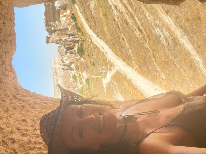 Woman wearing a cowboy hat framed by a cave opening looking out onto Cappadocia fairy chimneys