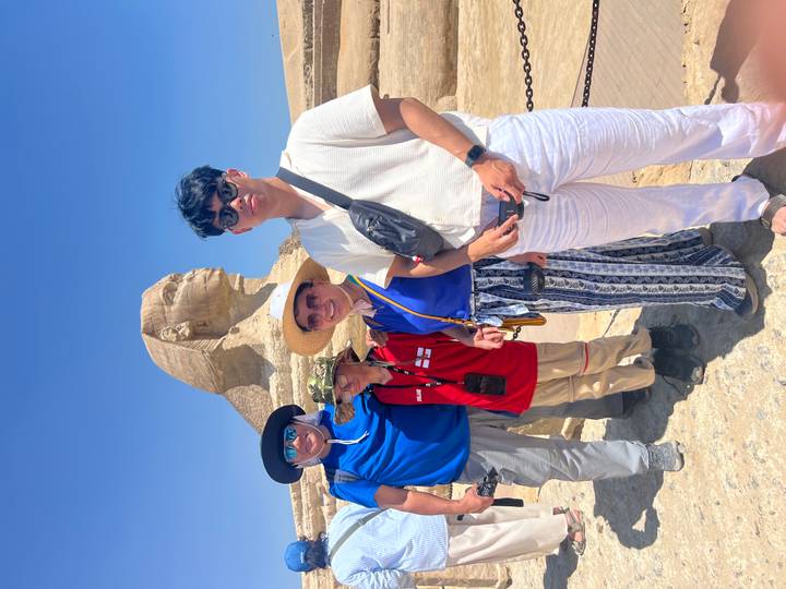 Smiling family posing in front of the Great Sphinx under a bright blue Egyptian sky