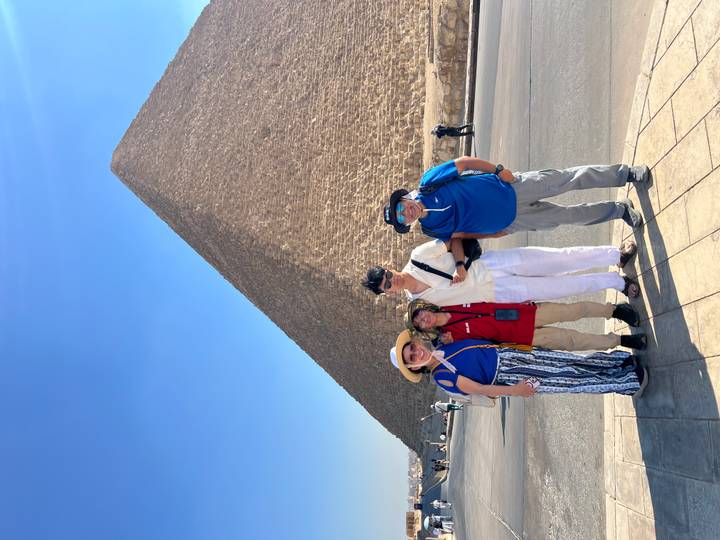 Family standing together with a towering pyramid of Giza rising behind them