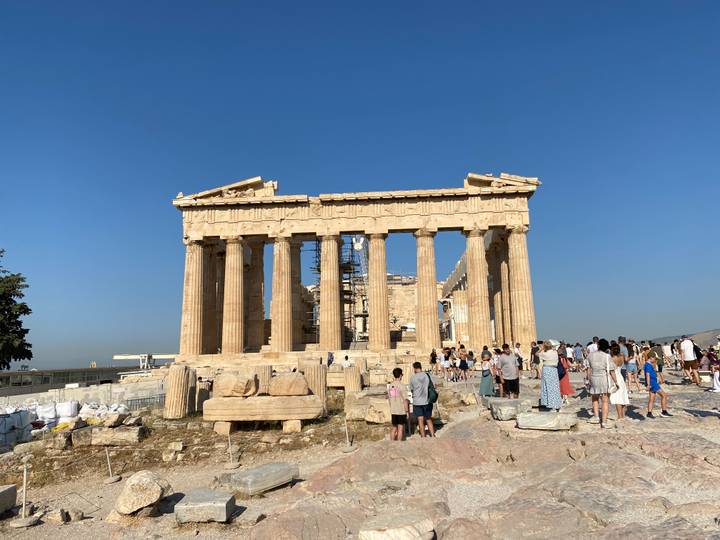 Visitors explore the ancient Parthenon atop the Acropolis under a clear blue sky