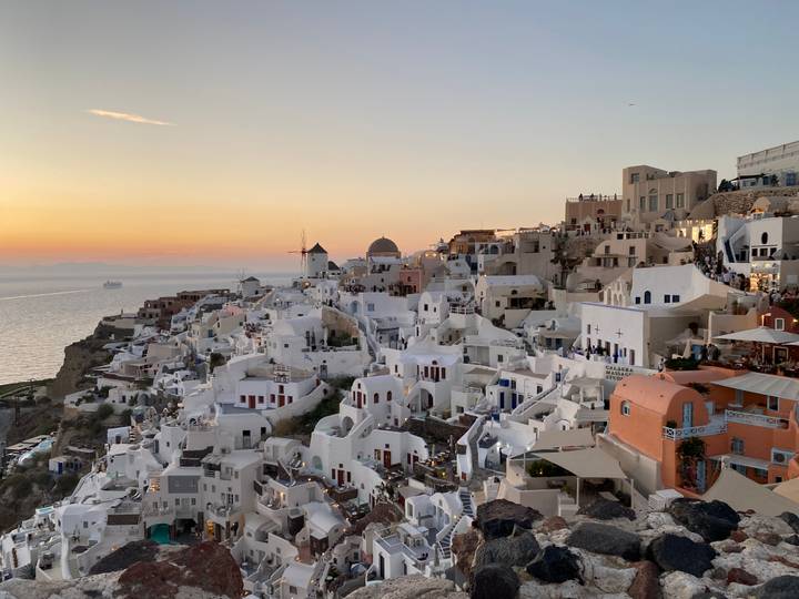 Iconic cliffside village of Oia with white cubic houses glowing at sunset over the Aegean Sea