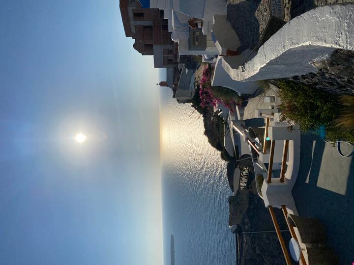 High sun over the caldera cliffs of Santorini with sparkling sea below