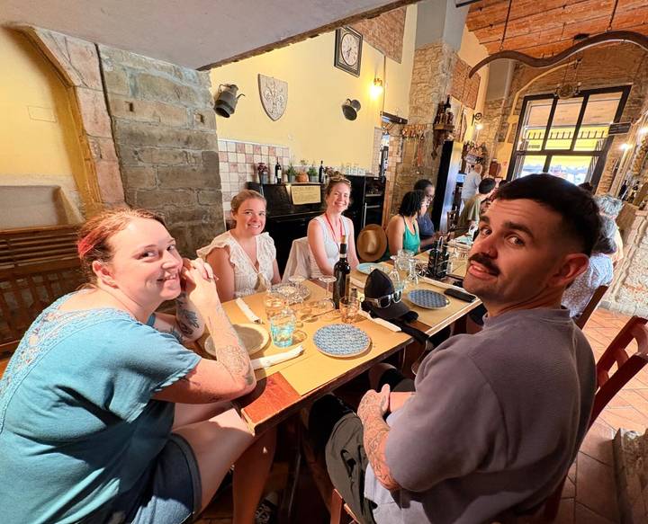 Friends enjoying food and wine around a rustic Italian restaurant table