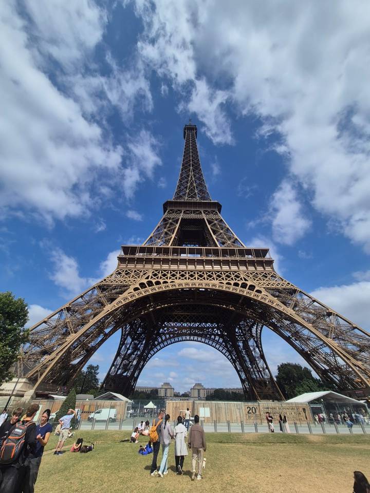 Upward perspective of the Eiffel Tower framed by a deep blue sky and scattered clouds