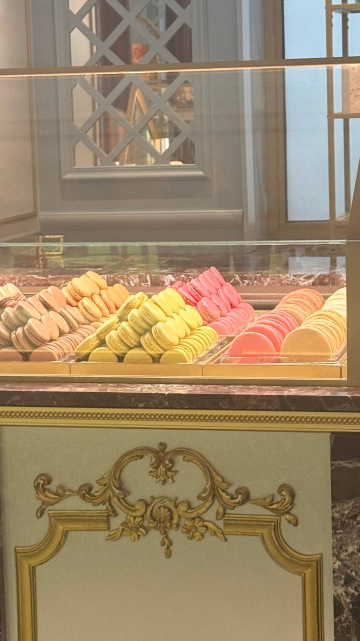 Display case filled with neatly stacked pastel-colored macarons in a patisserie
