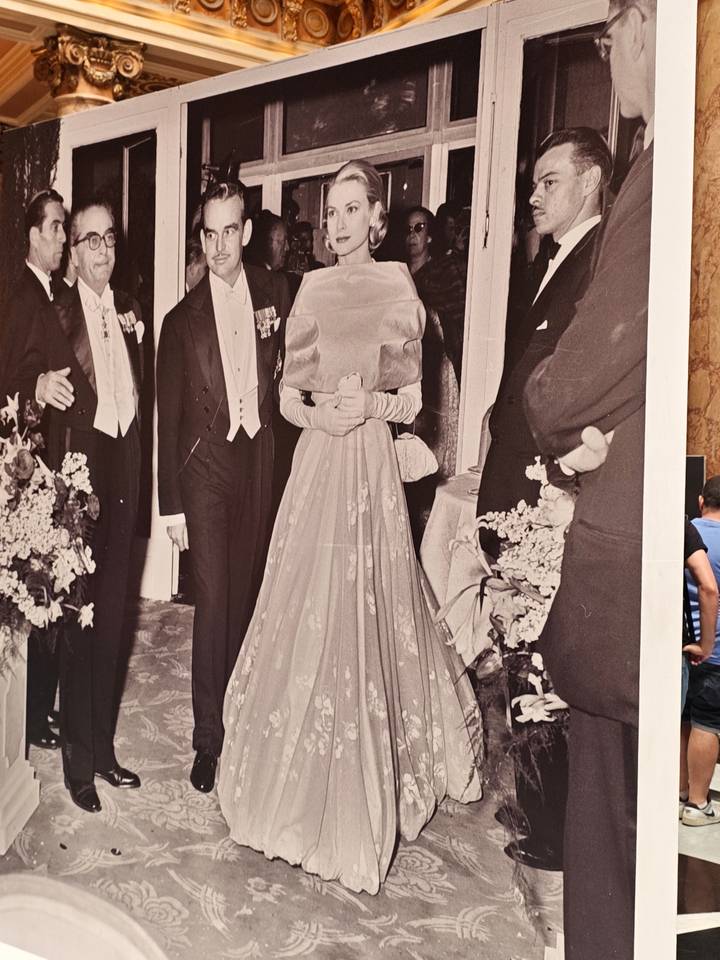 Exhibit photo of dignitaries in evening dress displayed in a museum with a visitor partly visible.