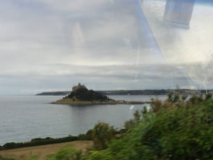 Distant view of an island castle across calm water seen through a vehicle window, slightly blurry