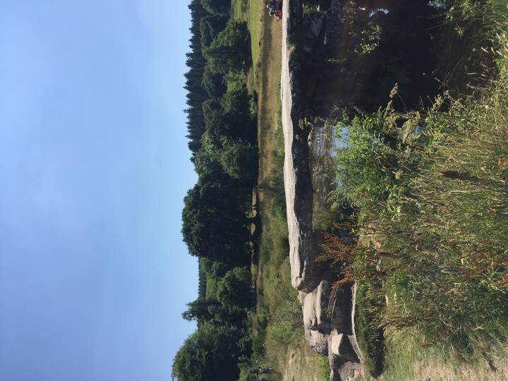 Rural stone clapper bridge crossing a small stream in a green countryside setting under clear skies