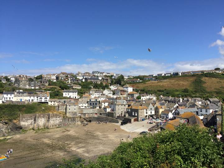 Panoramic view of Port Isaac’s clustered white and stone houses around its harbour on a sunny day