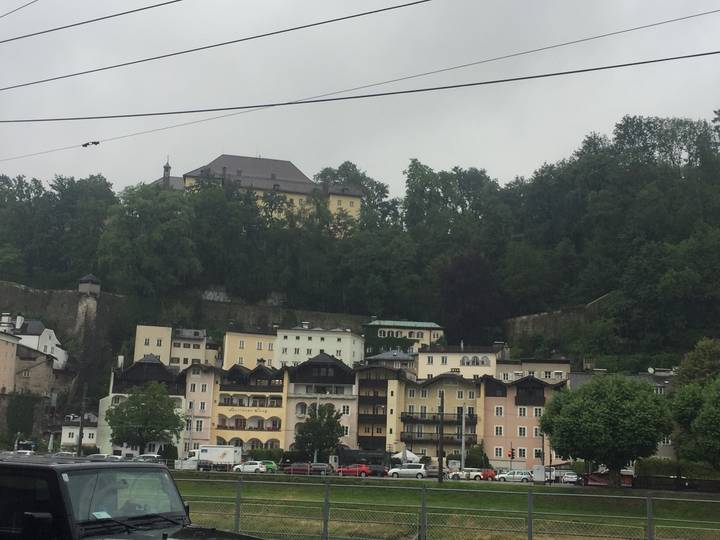 Cluster of multi-coloured hillside houses below a wooded cliff on a misty day