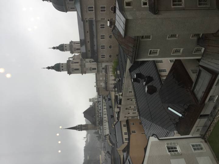 Rainy cityscape of Salzburg rooftops with cathedral domes and church spires seen from above